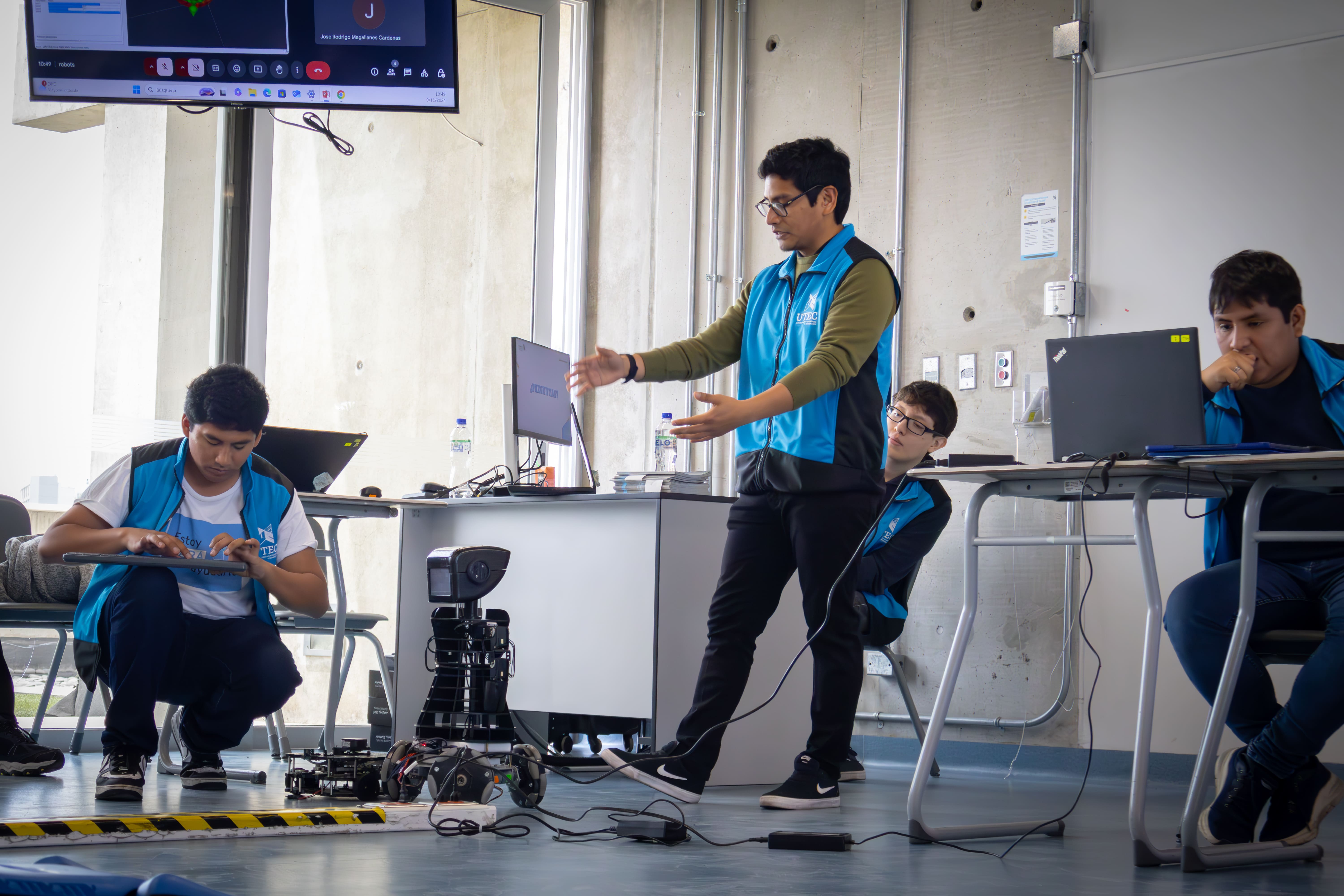 Dos estudiantes universitarios operando un brazo robótico industrial mediante una tablet en un laboratorio, ejemplificando la tipología de la innovación tecnológica y educativa