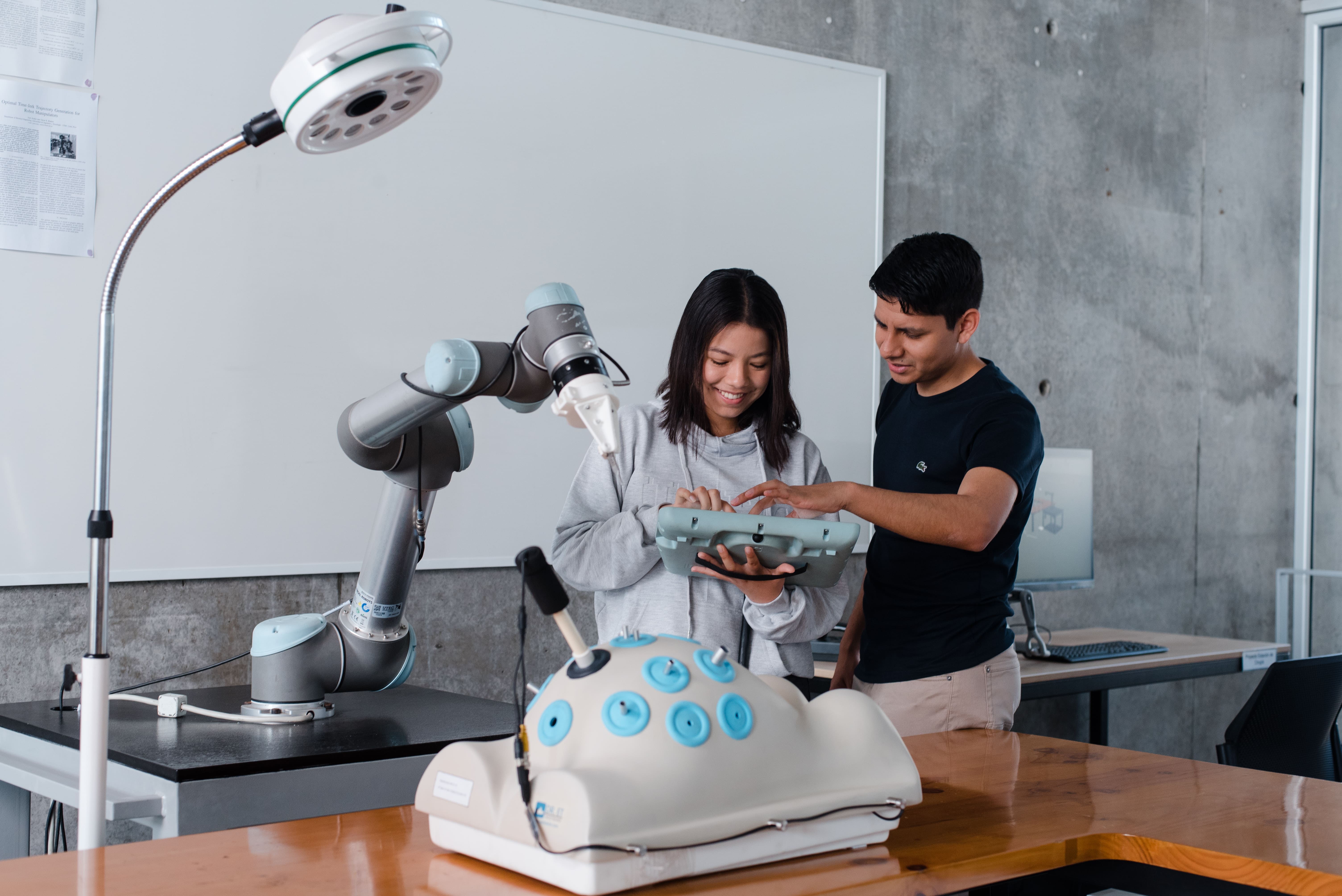 Grupo de jóvenes ingenieros presentando un prototipo de robot móvil en un taller, representando la tipología de la innovación incremental y el desarrollo de hardware.